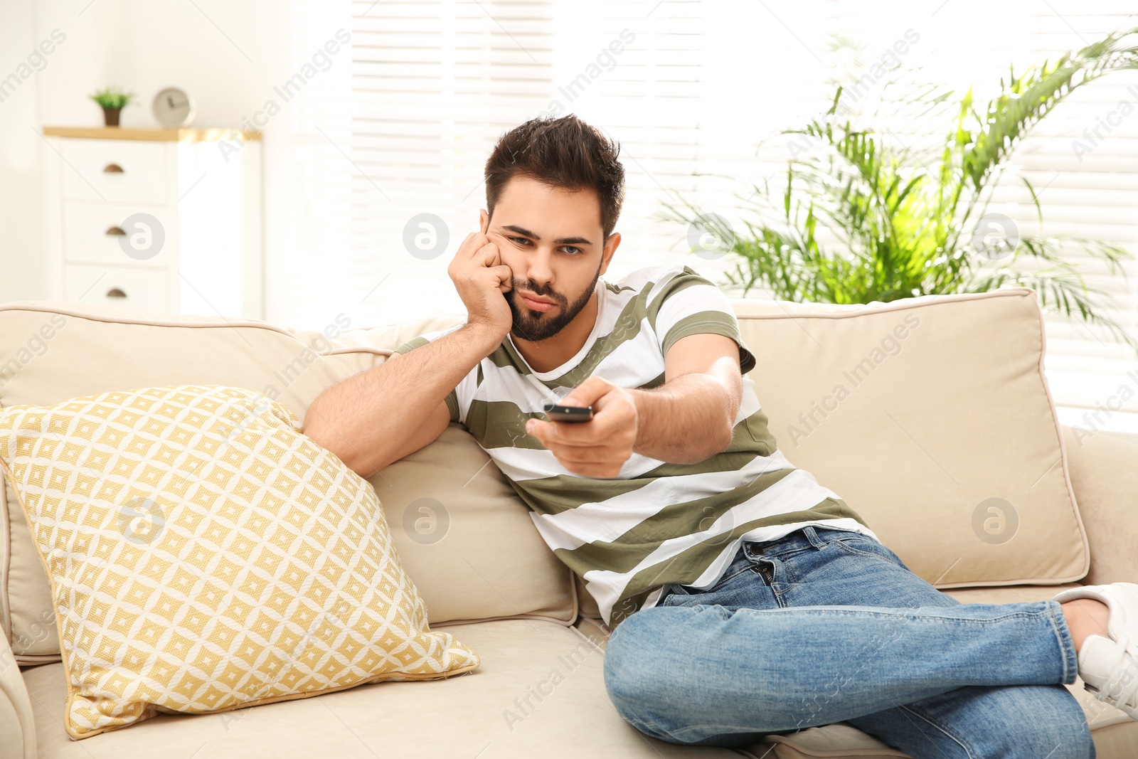 Photo of Lazy young man watching TV on sofa at home