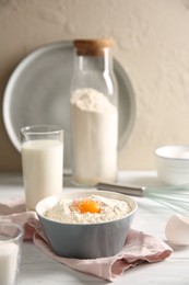 Making dough. Flour with yolk in bowl on white wooden table