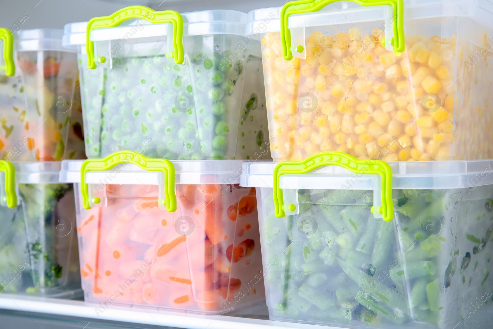 Photo of Containers with deep frozen vegetables in refrigerator