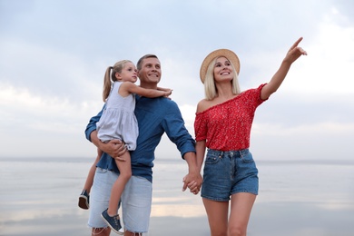 Photo of Happy family spending time together near sea on sunny summer day