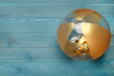 Photo of Bright beach ball on light blue wooden background, top view. Space for text