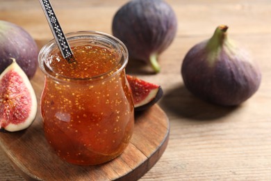 Glass jar with tasty sweet jam and fresh figs on wooden table, closeup. Space for text