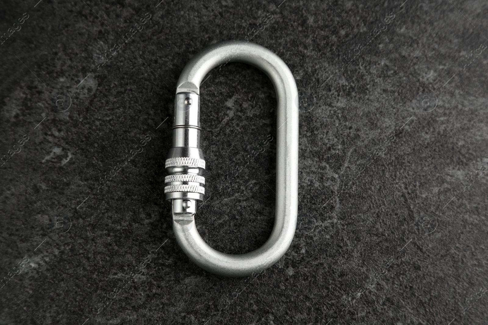 Photo of One metal carabiner on black table, top view