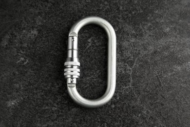Photo of One metal carabiner on black table, top view