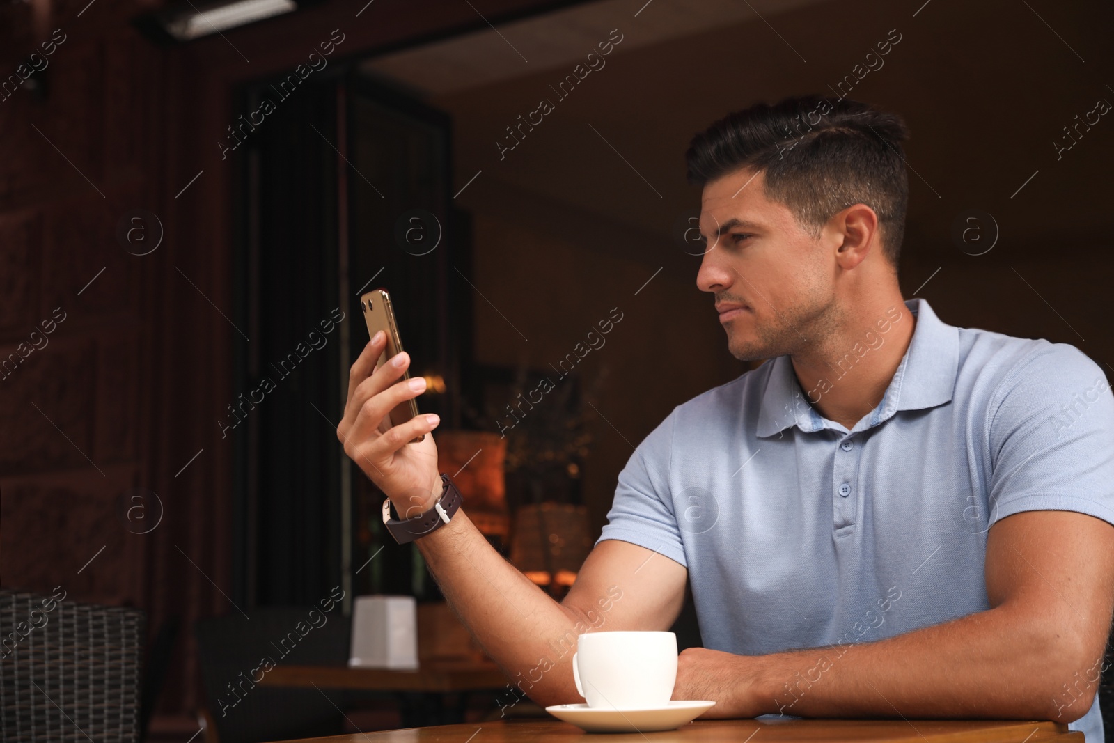 Photo of Man unlocking smartphone with facial scanner in cafe. Biometric verification