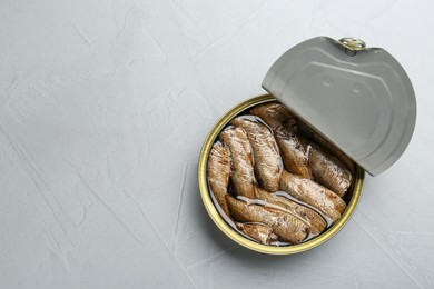 Photo of Open tin can of sprats on light grey table, top view. Space for text