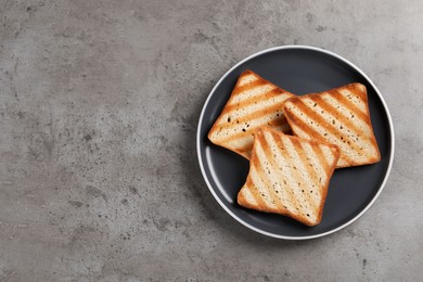 Plate with slices of delicious toasted bread on gray table, top view. Space for text