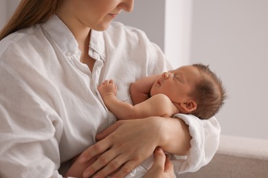 Mother holding her cute newborn baby indoors, closeup