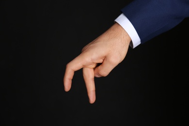 Businessman imitating walk with hand on black background, closeup. Finger gesture