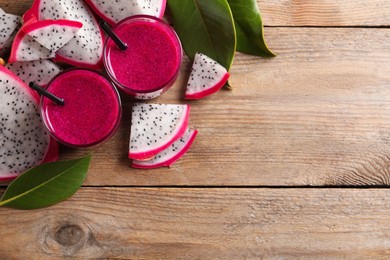 Photo of Delicious pitahaya smoothie and fresh fruits on wooden table, flat lay. Space for text
