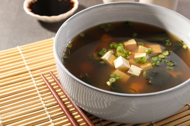 Bowl of delicious miso soup with tofu and chopsticks on table, closeup. Space for text