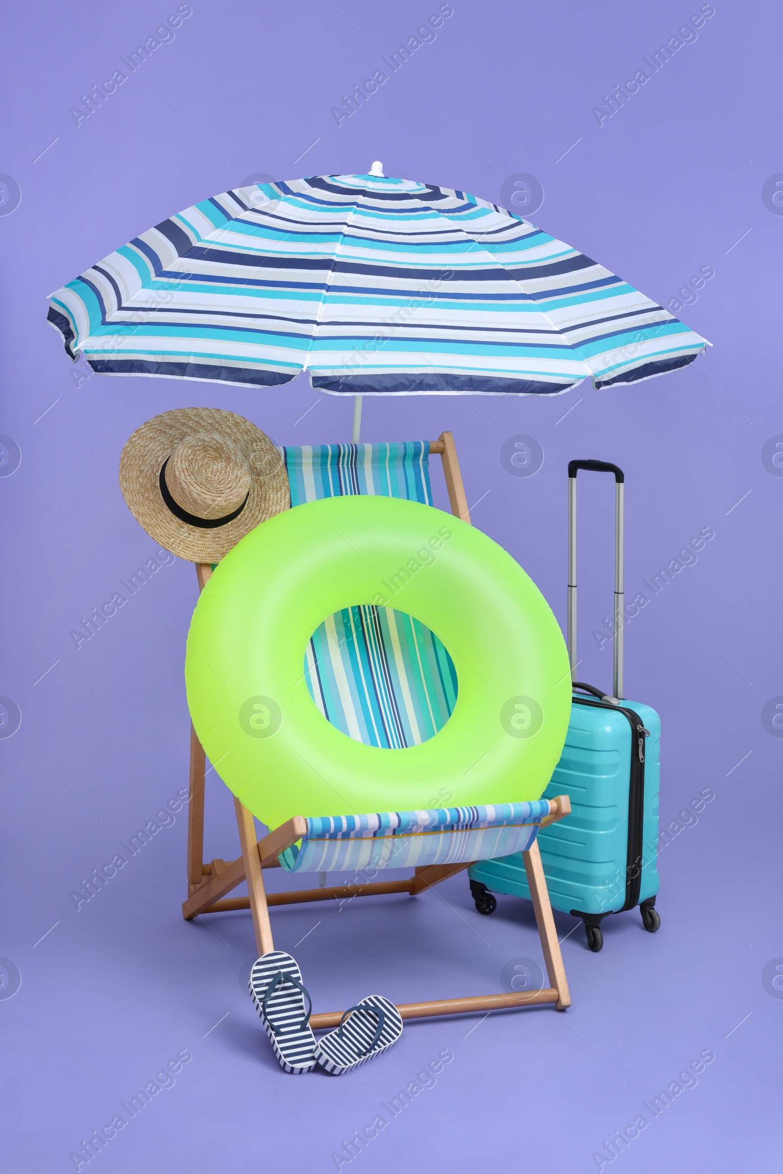 Deck chair, suitcase and beach accessories on purple background. Summer vacation Photo of Deck chair, suitcase and beach accessories on purple background. Summer vacation