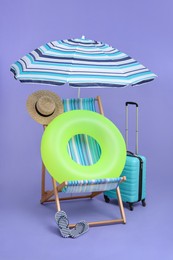 Photo of Deck chair, suitcase and beach accessories on purple background. Summer vacation