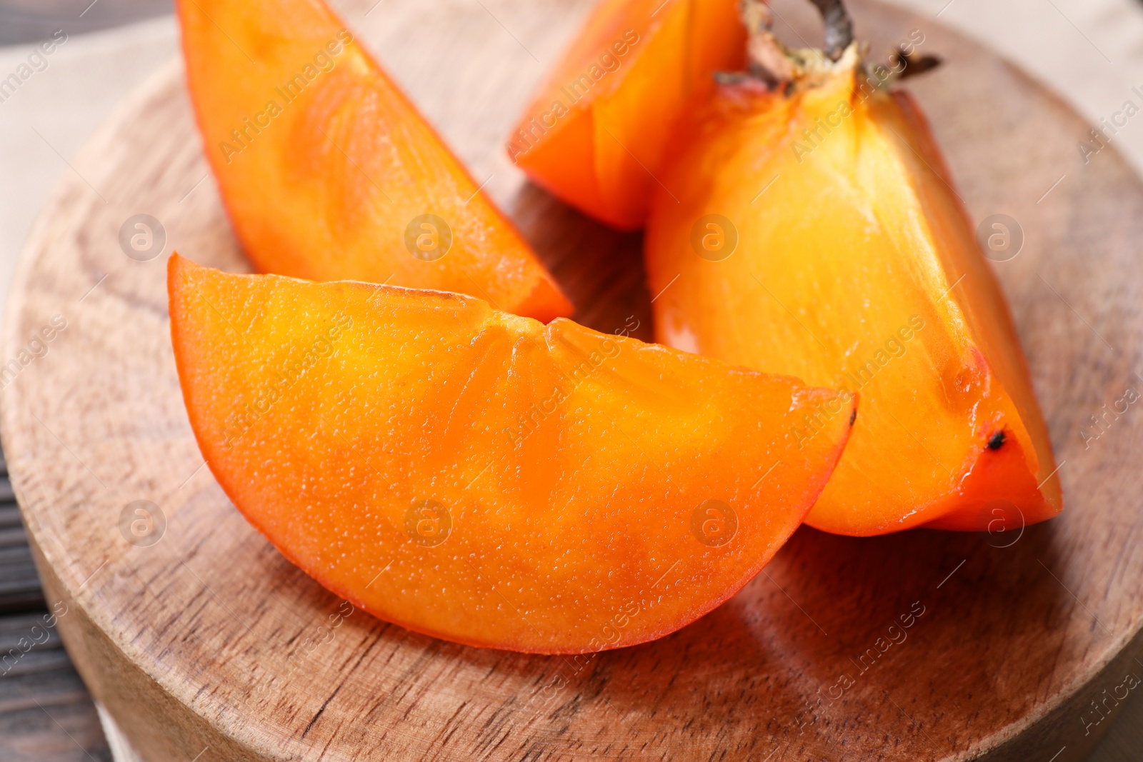 Photo of Pieces of delicious persimmons on wooden board, closeup