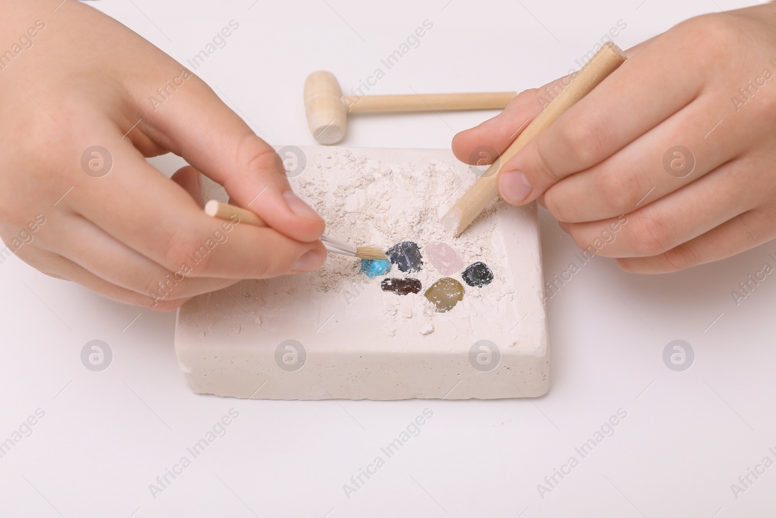 Photo of Child playing with Excavation kit at white table, closeup. Educational toy for motor skills