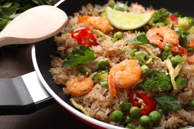 Tasty rice with shrimps and vegetables in frying pan on table, closeup