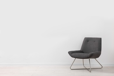 Photo of Comfortable armchair near white wall indoors. Space for text