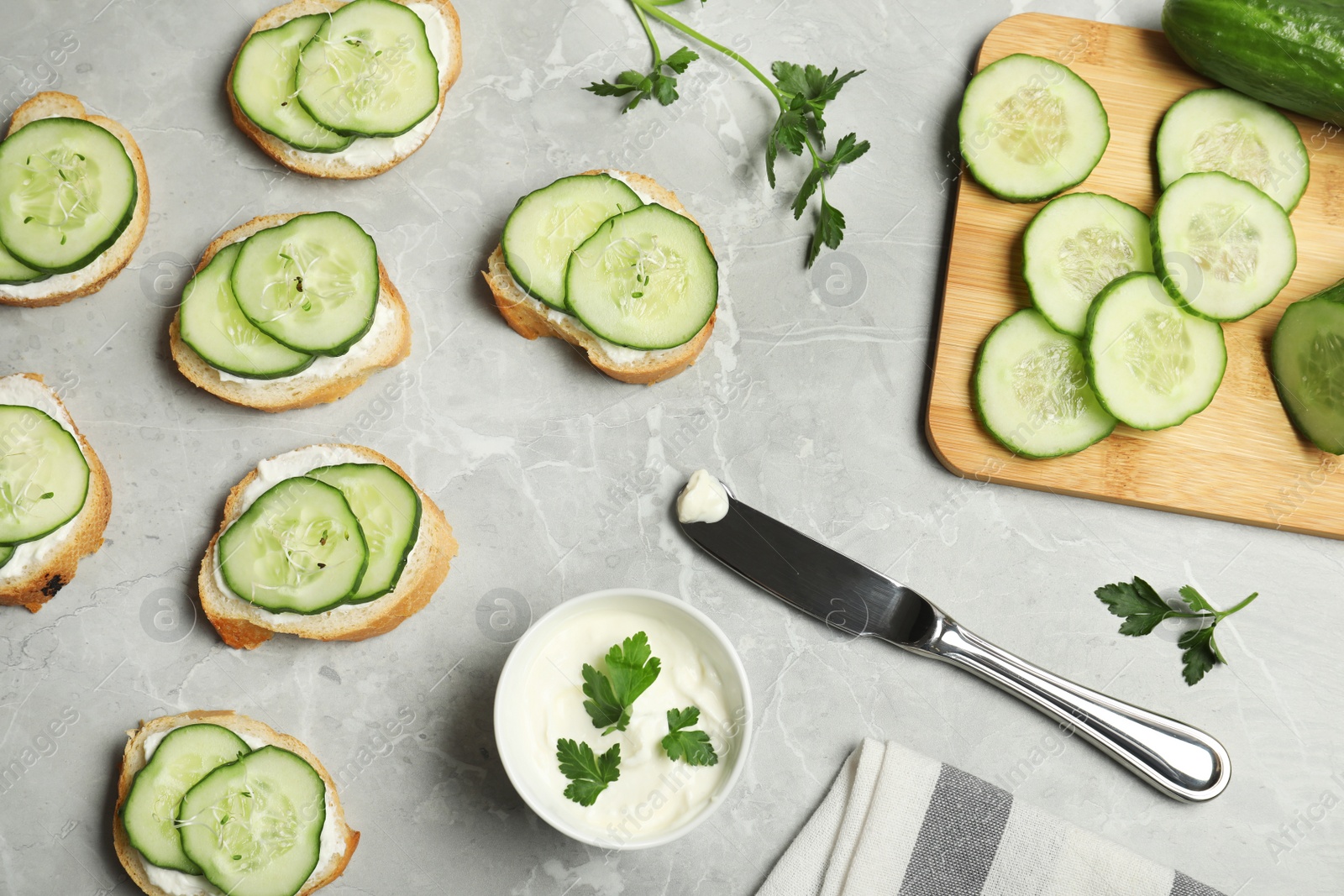 Photo of Flat lay composition with traditional English cucumber sandwiches and ingredients on grey background