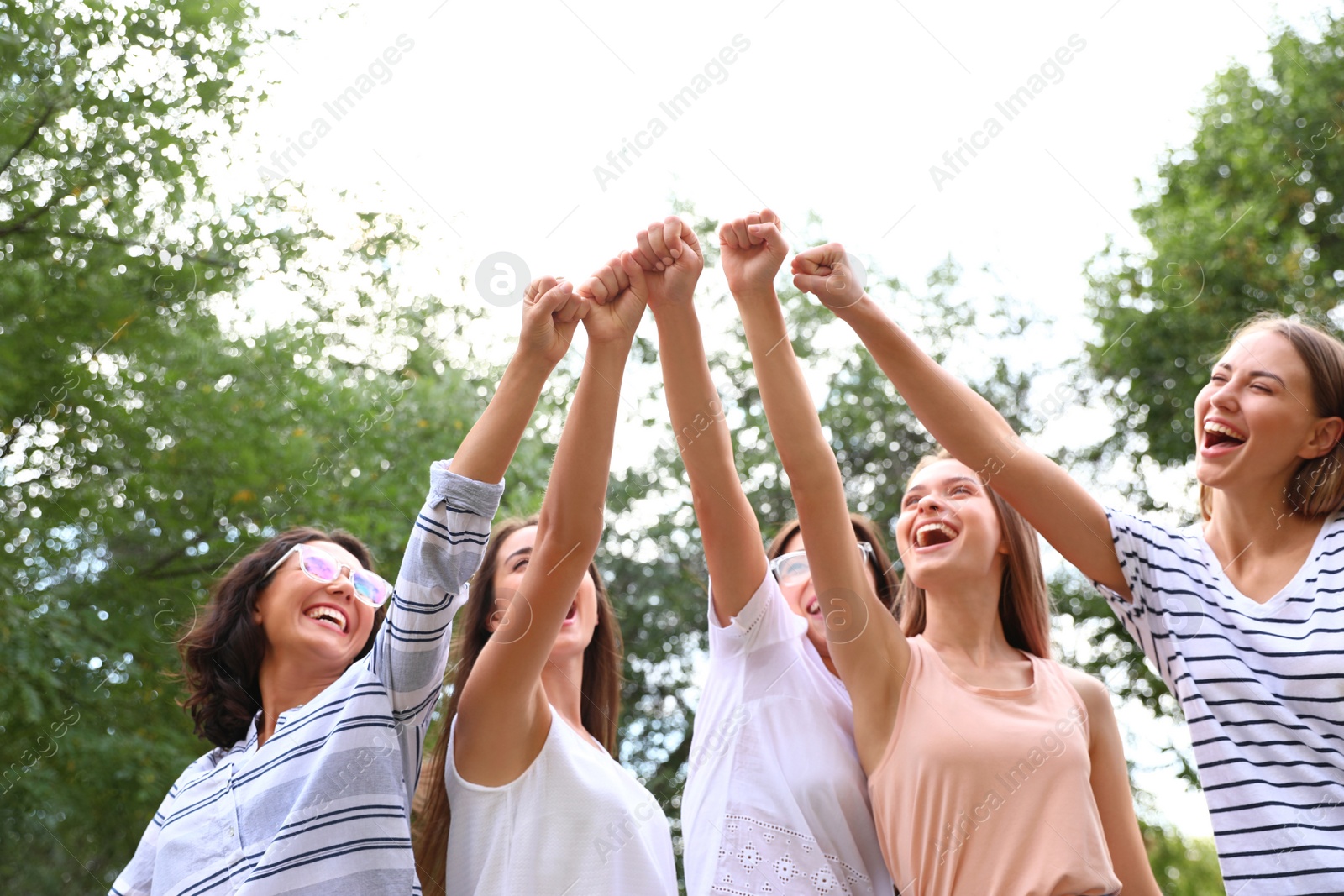 Photo of Happy women raising hands outdoors. Girl power concept