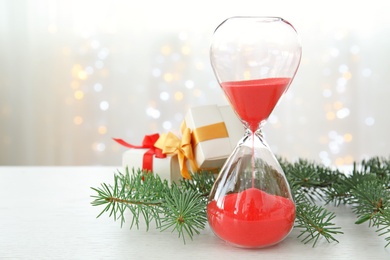 Photo of Hourglass with gifts and decor on table. Christmas countdown