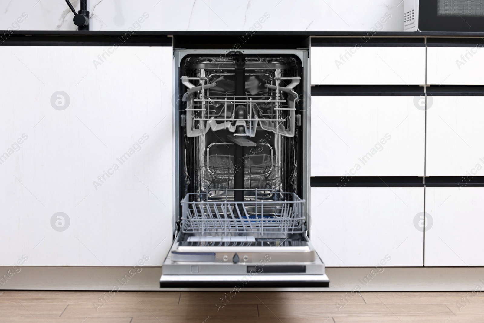 Photo of Open clean empty dishwasher in kitchen. Home appliance