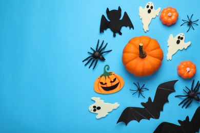 Photo of Flat lay composition with bats, pumpkins, ghosts and spiders on light blue background, space for text. Halloween celebration