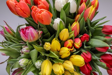 Photo of Beautiful colorful tulip flowers on grey background, closeup