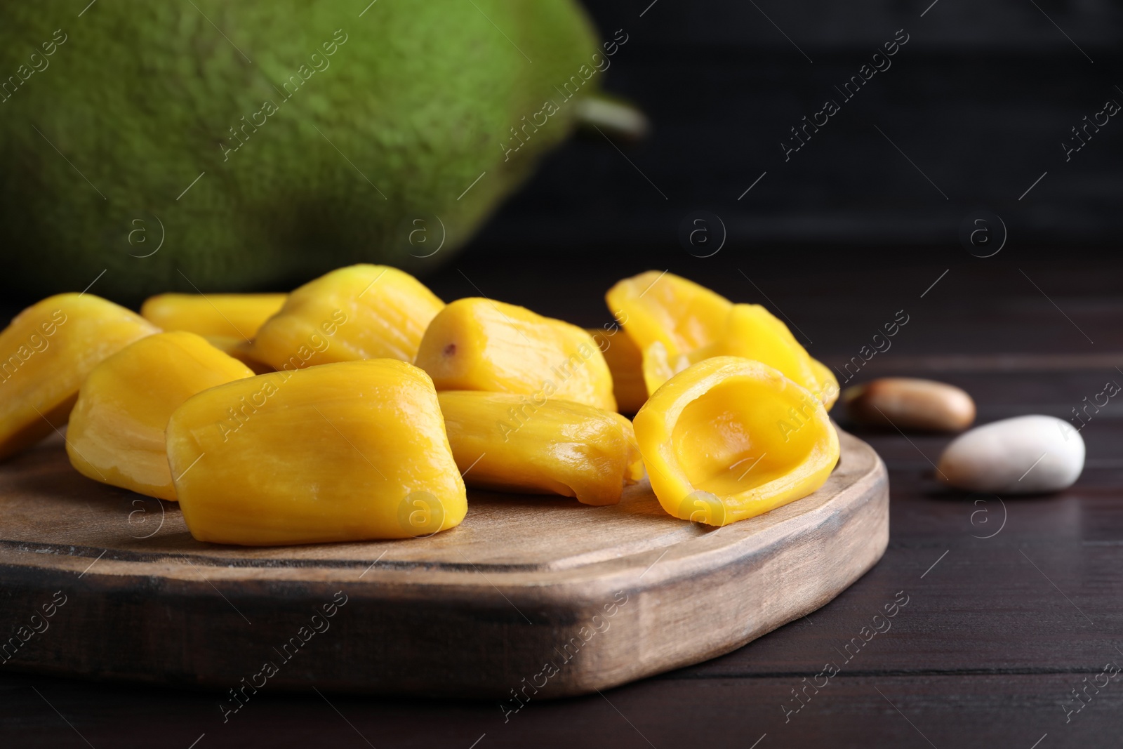 Photo of Fresh exotic jackfruit bulbs on black wooden table, closeup