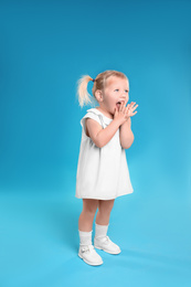 Cute little girl posing on light blue background