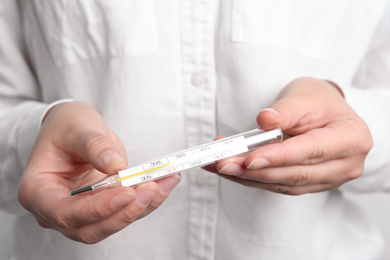 Photo of Closeup view of woman holding mercury thermometer