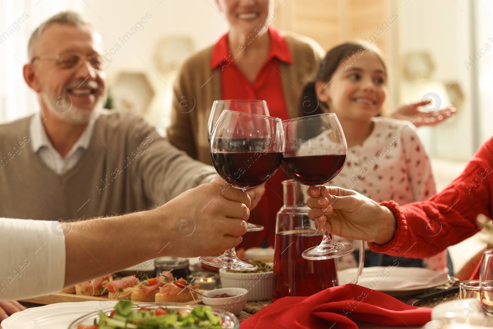 Photo of Family clinking glasses of wine at festive dinner, focus on hands. Christmas celebration