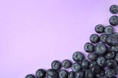 Tasty ripe blueberries on violet background, flat lay with space for text