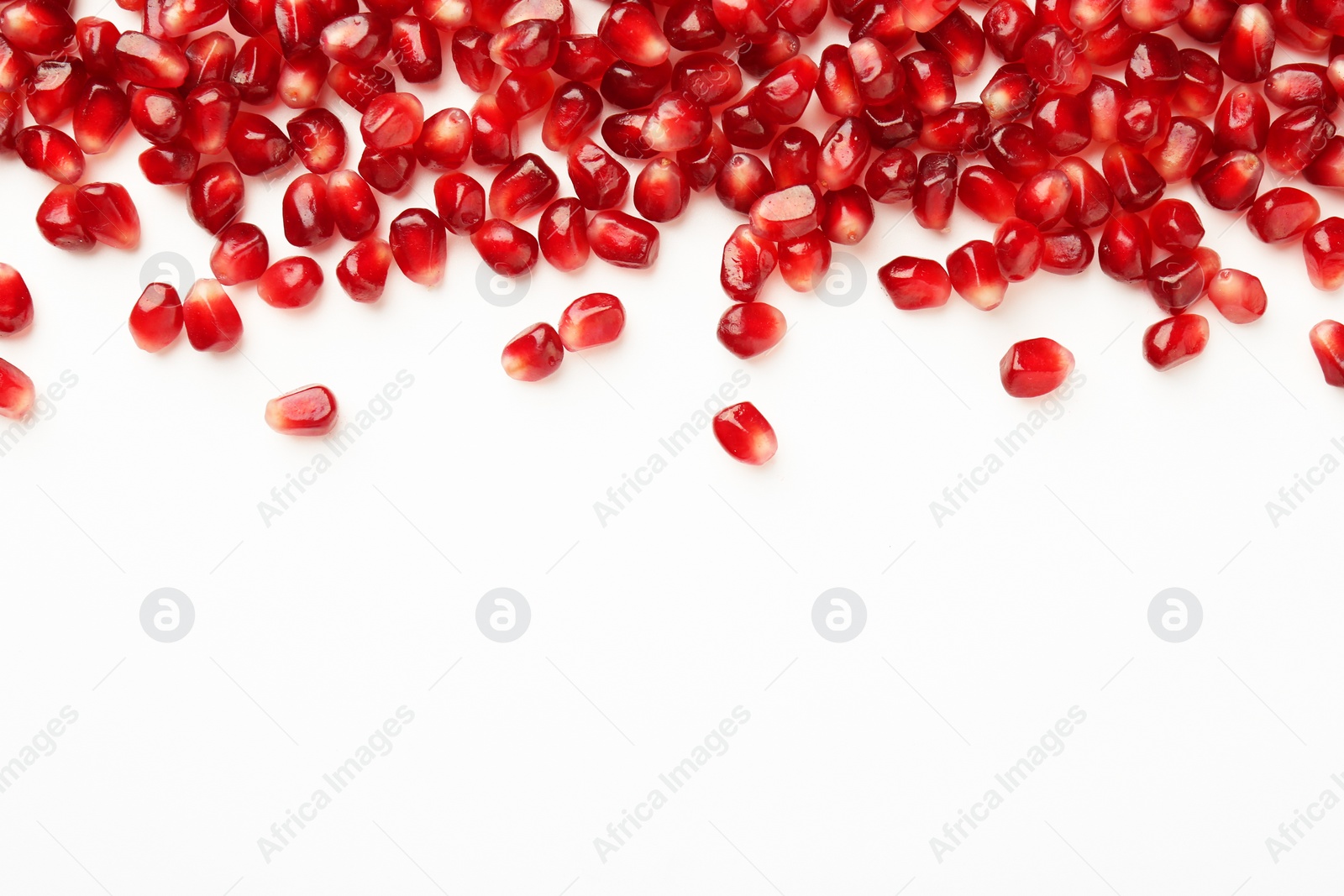 Photo of Many ripe juicy pomegranate grains on white background, flat lay. Space for text