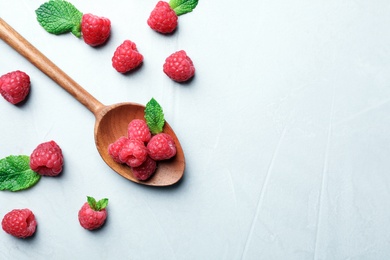 Spoon with ripe aromatic raspberries on table, top view