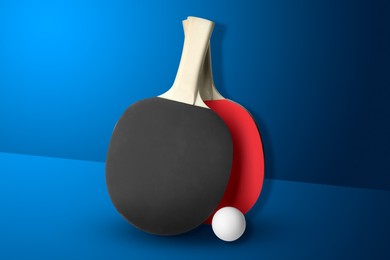 Image of Ping pong paddles and ball on blue background. Table tennis championship