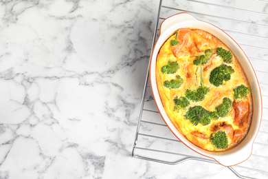 Tasty broccoli casserole in baking dish on cooling rack, top view. Space for text