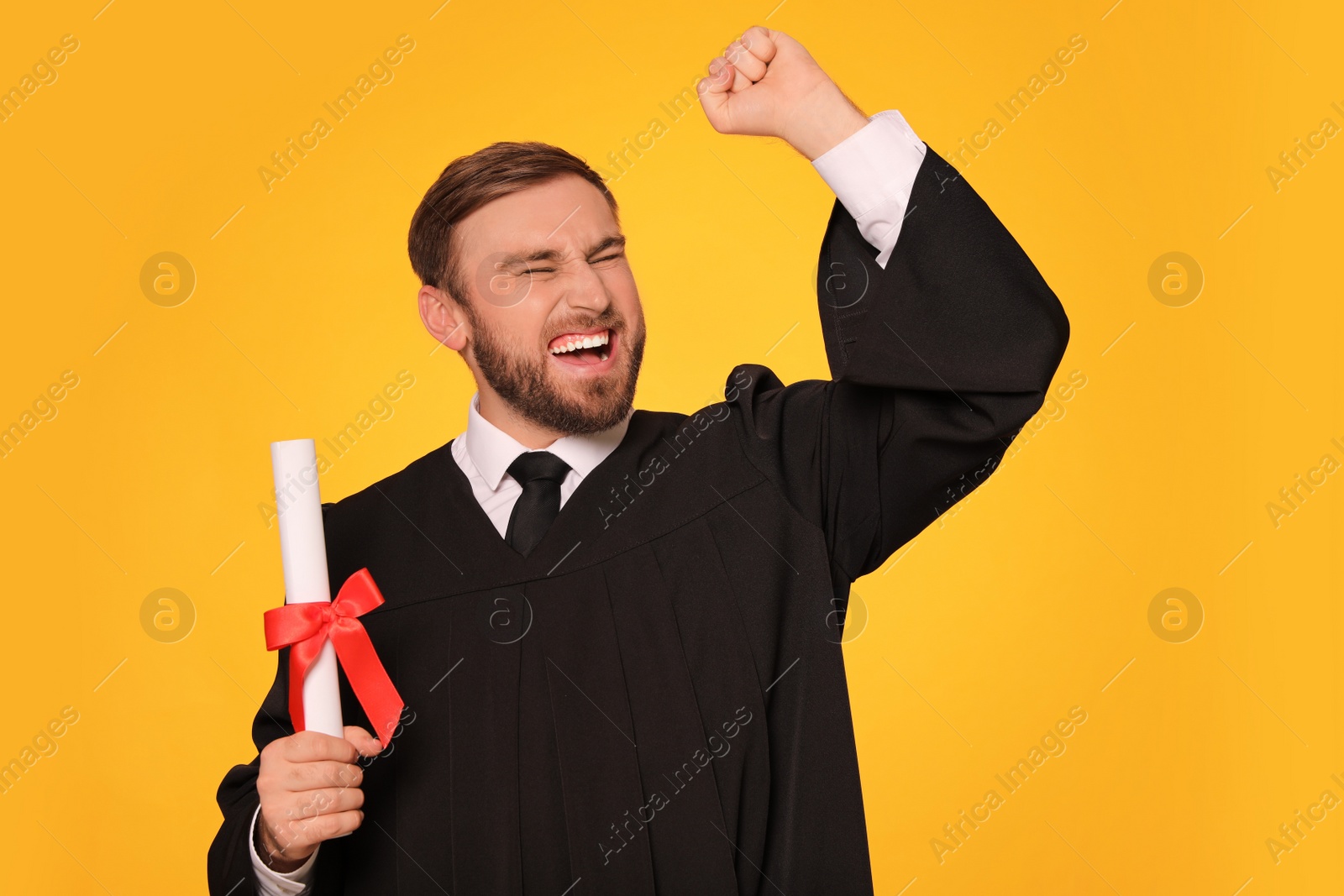 Photo of Emotional student with diploma on yellow background