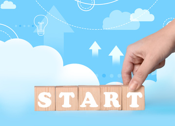 Woman making word START with wooden cubes on light blue background, closeup