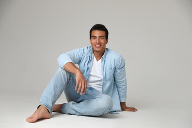 Handsome young African-American man sitting on light background. Space for text