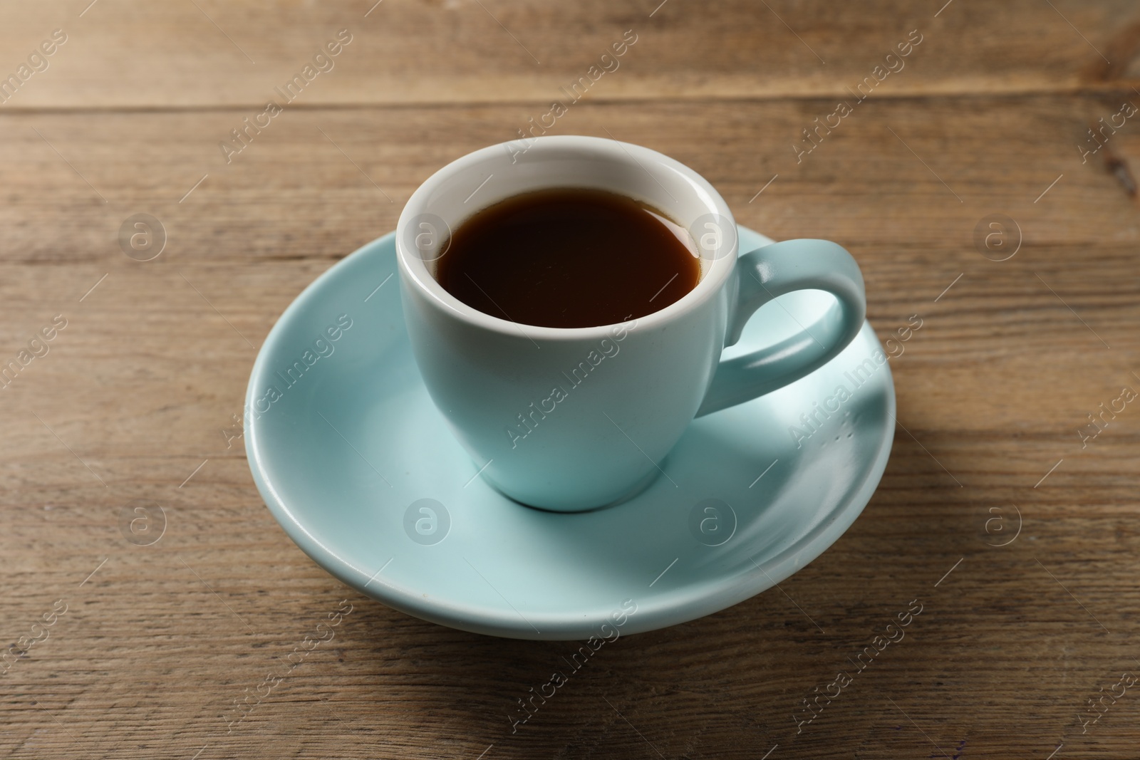 Photo of Tasty coffee in cup on wooden table, closeup