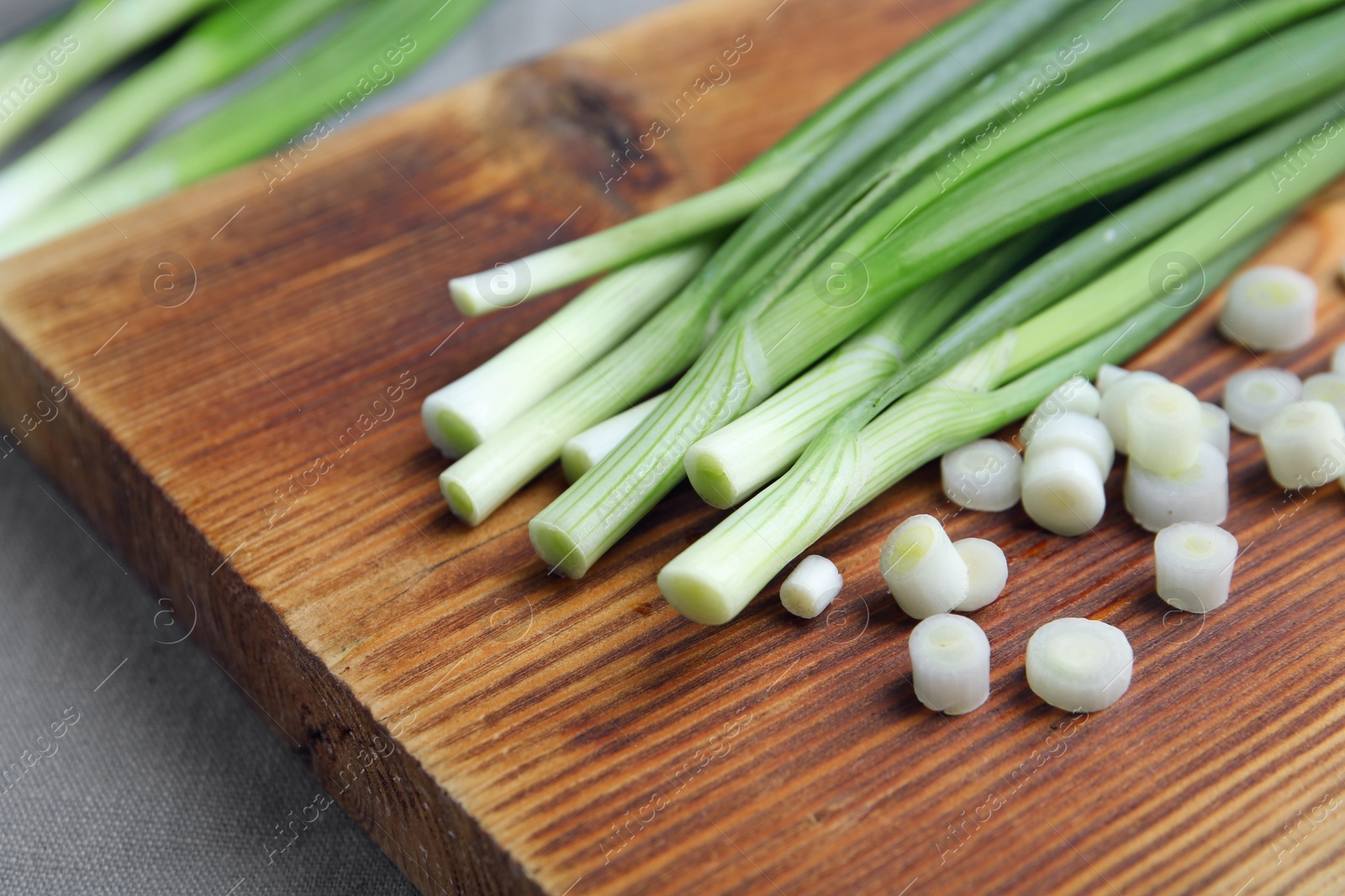 Photo of Wooden board with fresh green onion, closeup