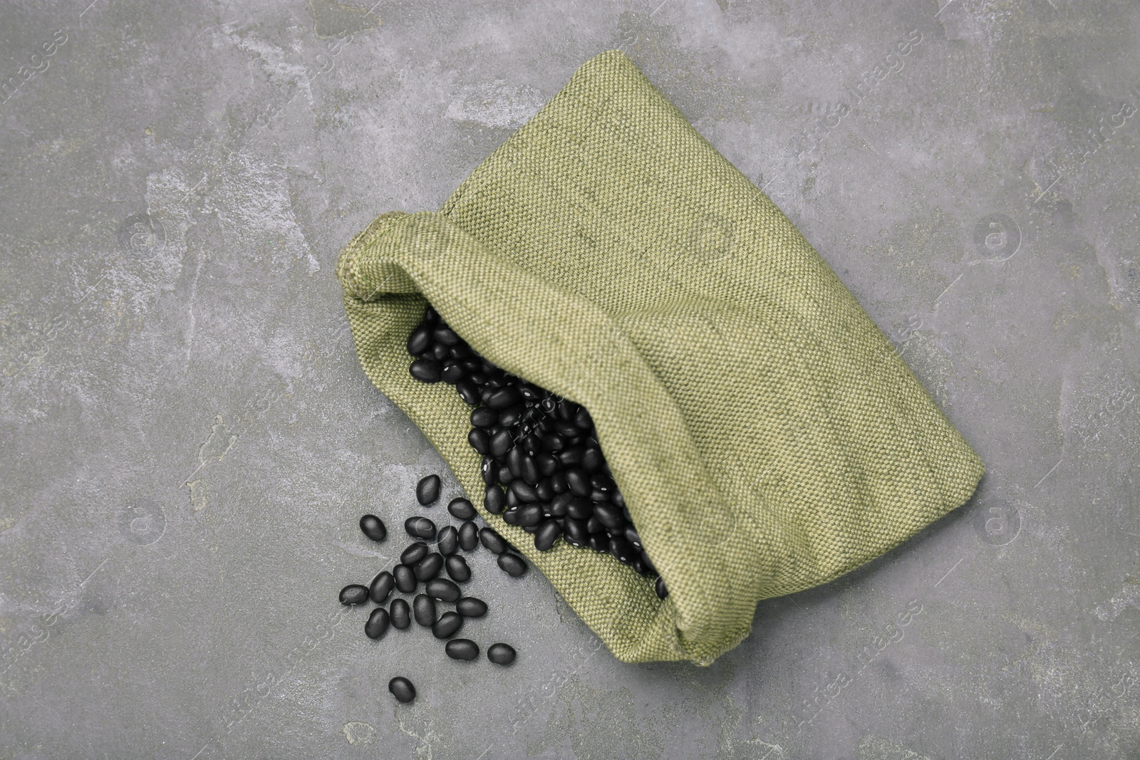 Photo of Sack of raw black beans on grey table, top view