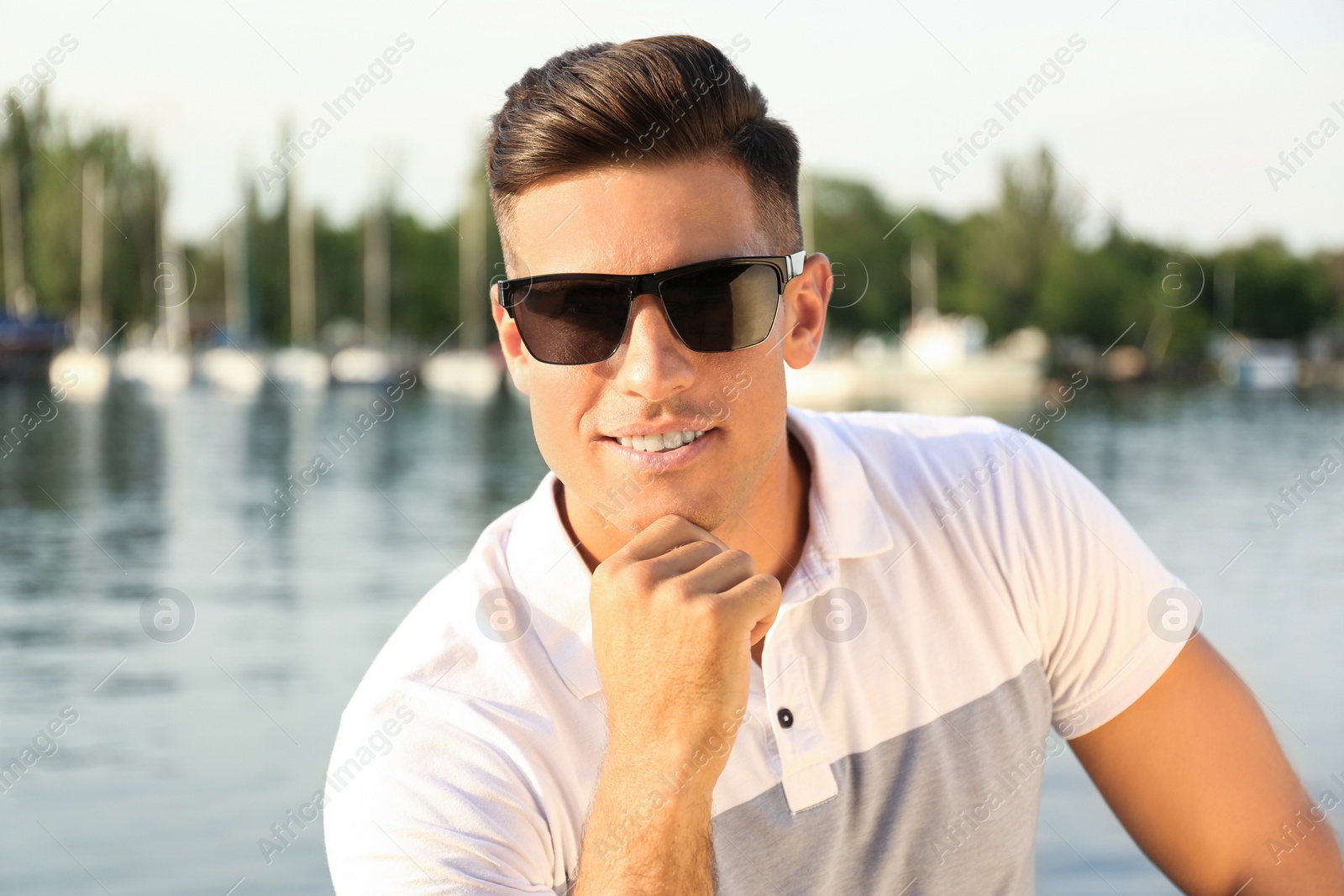 Photo of Handsome man wearing stylish sunglasses near river