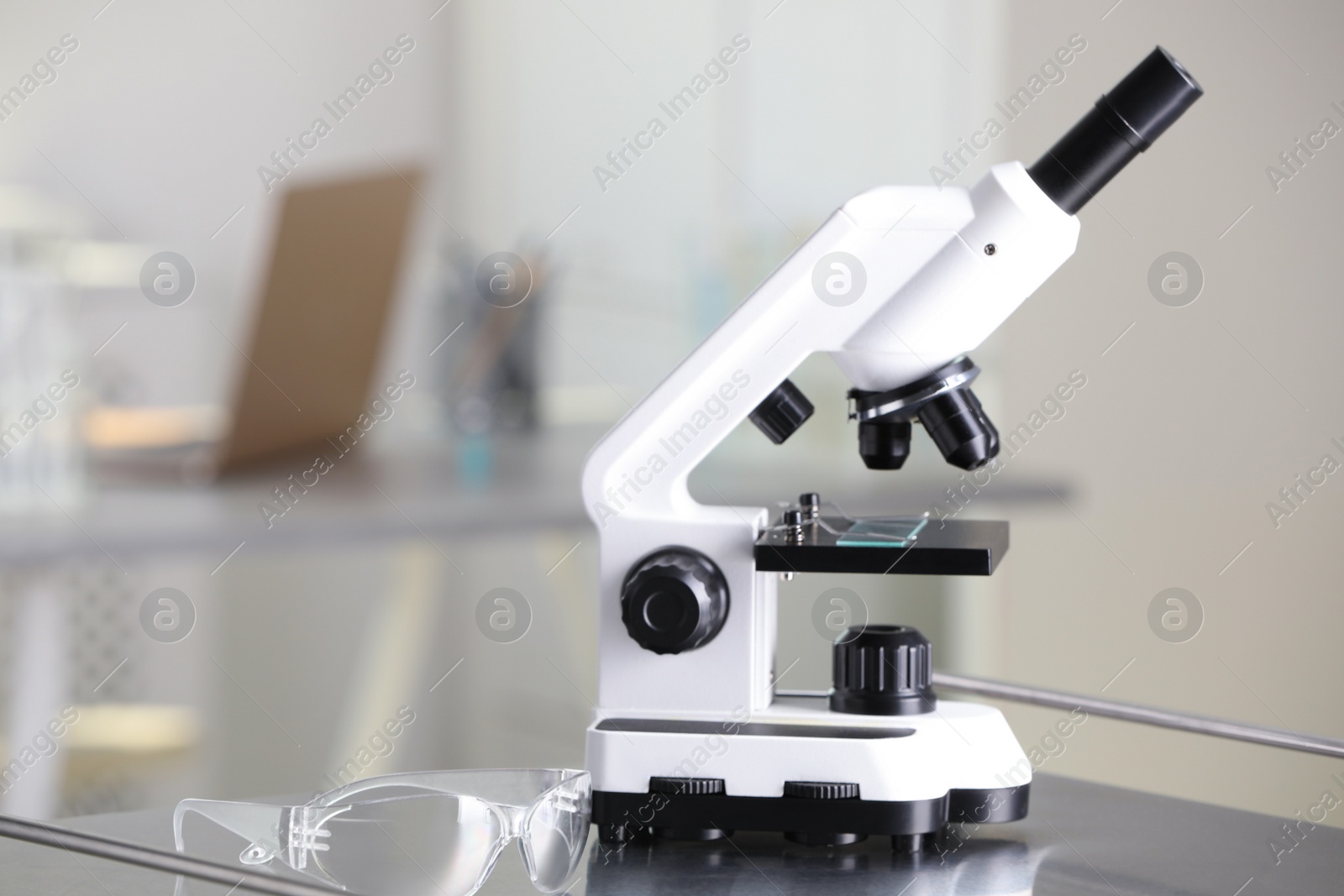 Photo of Modern medical microscope on metal table in laboratory, space for text