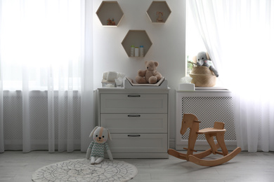 Beautiful baby room interior with toys and modern changing table