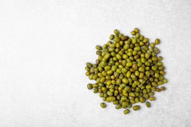 Photo of Pile of green mung beans on light grey table, top view. Space for text