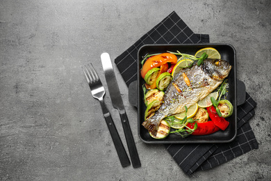 Photo of Delicious roasted fish and vegetables on grey table, flat lay. Space for text