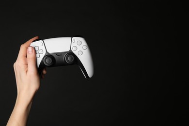 Photo of Woman holding game controller on black background, closeup. Space for text