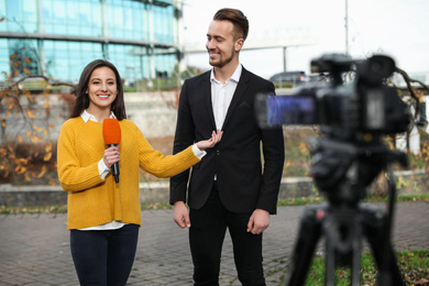 Photo of Young journalist interviewing businessman on city street