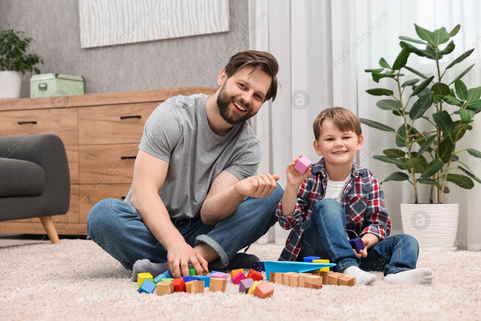 Photo of Happy dad and son playing with cubes at home